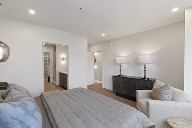 bedroom featuring connected bathroom and light hardwood / wood-style flooring