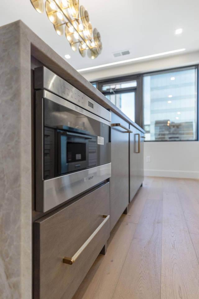 kitchen with stainless steel oven and light wood-type flooring