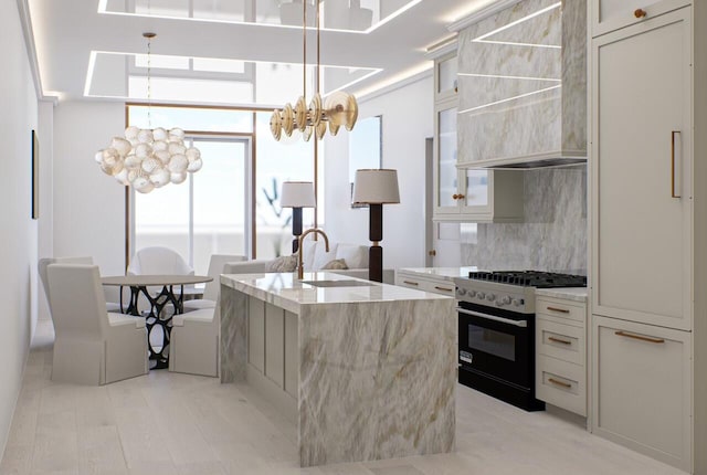 kitchen featuring custom exhaust hood, decorative backsplash, a kitchen island with sink, stainless steel range, and light hardwood / wood-style floors