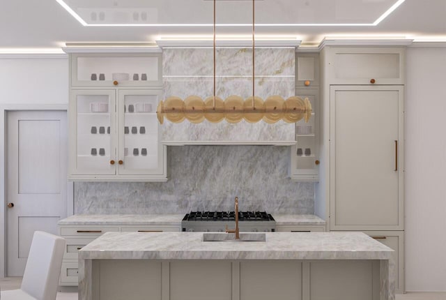 kitchen featuring white cabinets, hanging light fixtures, backsplash, and an island with sink