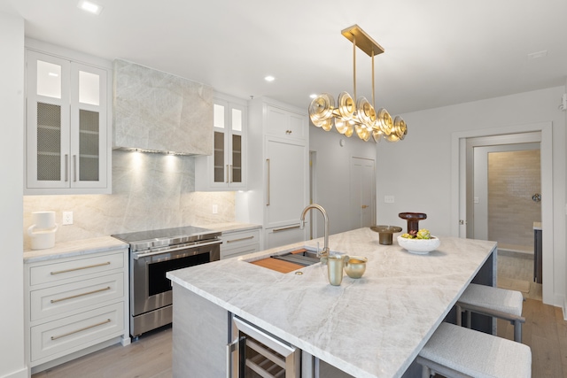 kitchen featuring white cabinetry, stainless steel range with electric stovetop, and a kitchen island with sink