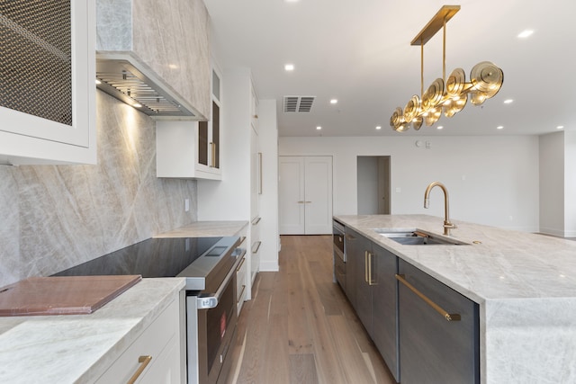 kitchen featuring appliances with stainless steel finishes, white cabinetry, hardwood / wood-style flooring, wall chimney exhaust hood, and sink