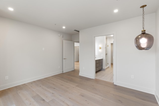 unfurnished bedroom featuring light hardwood / wood-style floors and connected bathroom