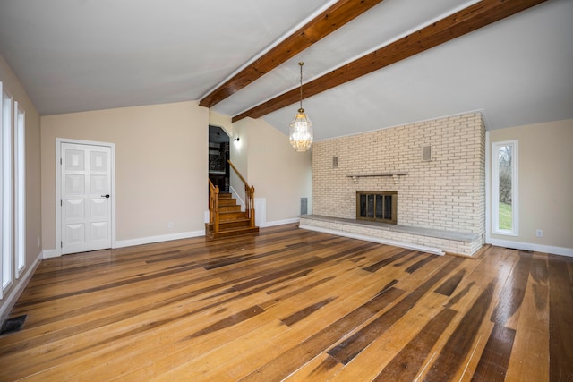 unfurnished living room with dark hardwood / wood-style floors, a fireplace, vaulted ceiling with beams, and a notable chandelier