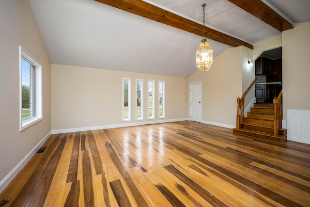 unfurnished living room featuring lofted ceiling with beams, dark hardwood / wood-style floors, and an inviting chandelier