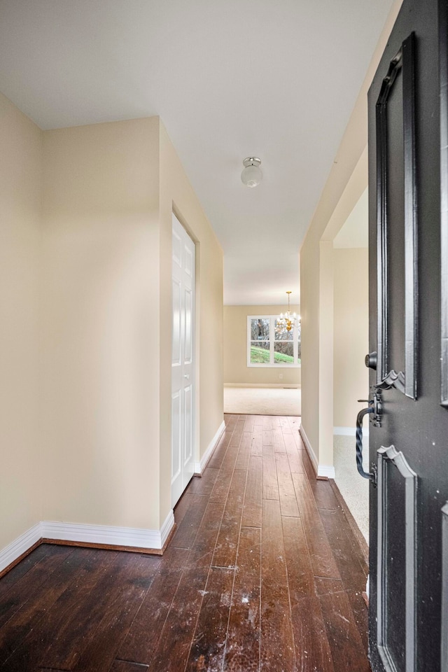 hallway featuring dark hardwood / wood-style floors and a notable chandelier