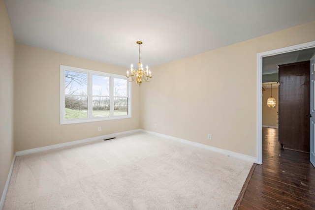 empty room featuring dark carpet and a chandelier