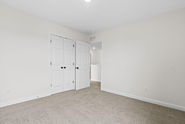 unfurnished bedroom with light carpet and a closet