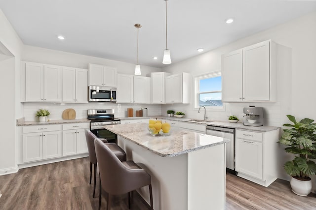 kitchen with appliances with stainless steel finishes, white cabinetry, and a kitchen island