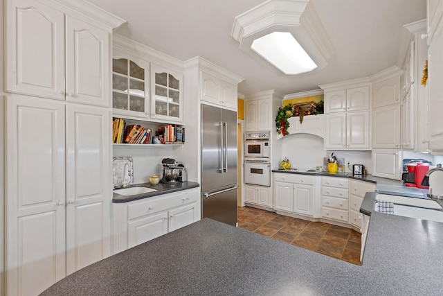 kitchen featuring sink, white cabinets, dark tile floors, and built in refrigerator