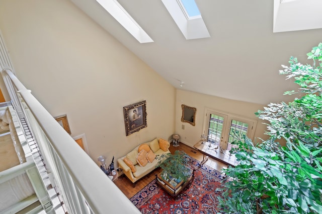 living room with high vaulted ceiling, hardwood / wood-style flooring, and a skylight