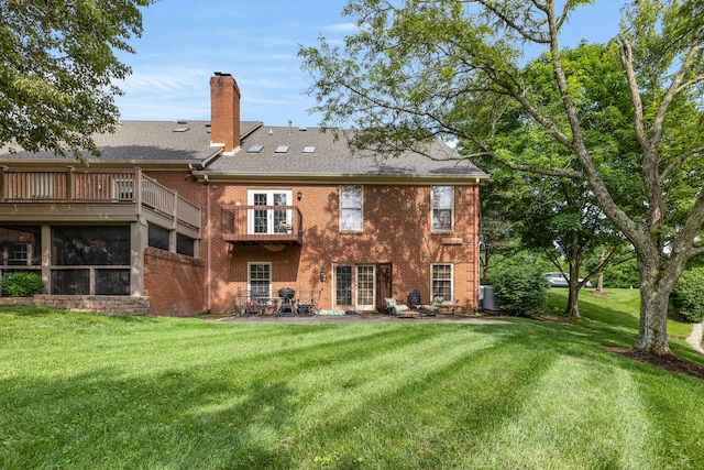 back of property with a yard, central AC unit, and a balcony