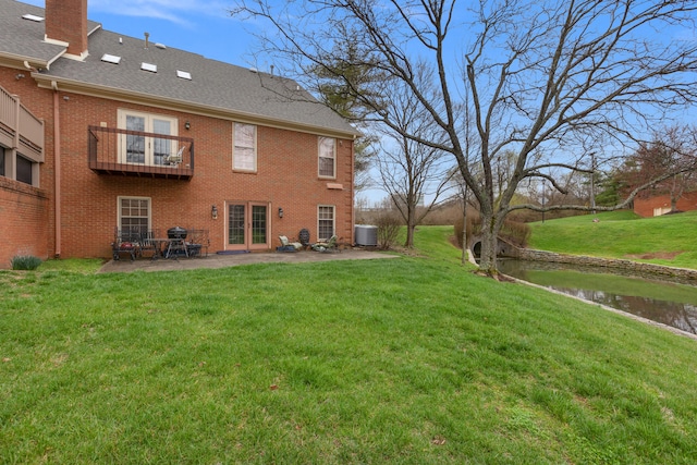 view of yard with a balcony, a patio area, central air condition unit, and french doors