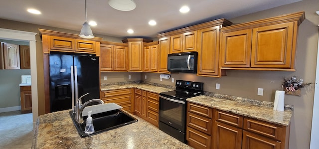 kitchen featuring hanging light fixtures, light stone countertops, sink, and black appliances