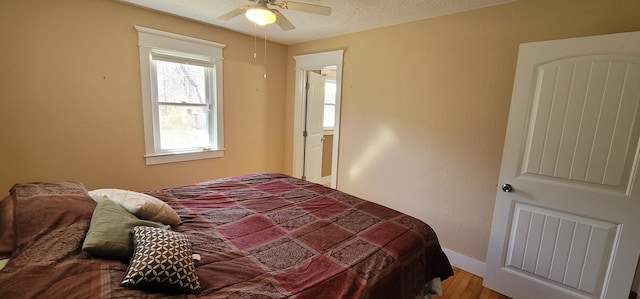 bedroom with a textured ceiling, ceiling fan, and hardwood / wood-style flooring