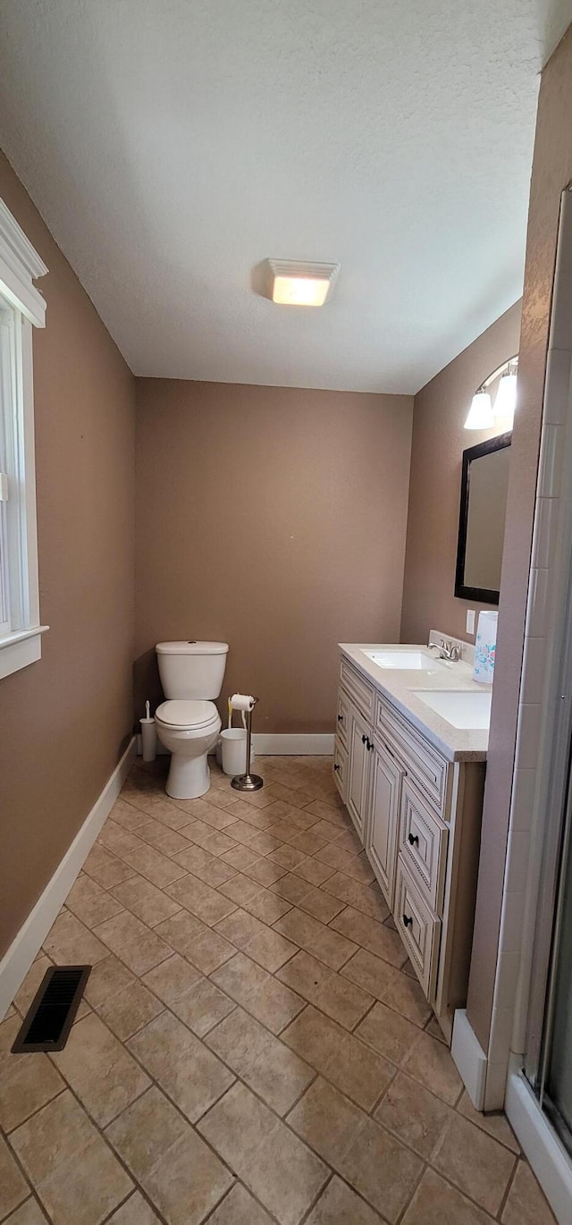 bathroom featuring vanity, walk in shower, and toilet