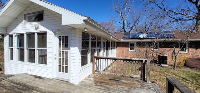 exterior space featuring a wooden deck, central AC unit, a sunroom, and solar panels