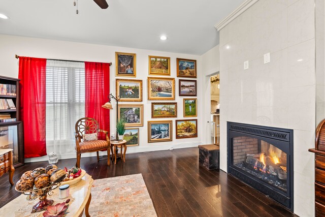 sitting room with ceiling fan, dark hardwood / wood-style floors, and a tiled fireplace