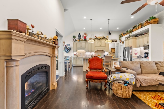 living room featuring ceiling fan, lofted ceiling, wood-type flooring, and a tile fireplace