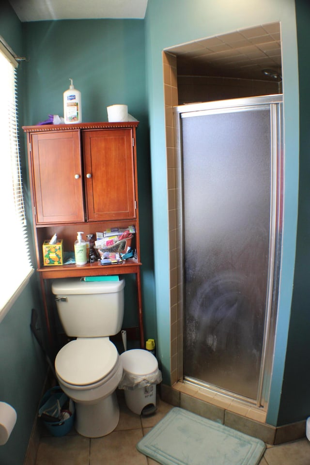 bathroom featuring tile flooring, a shower with door, and toilet