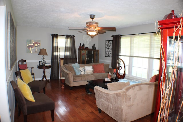 living room with a textured ceiling, ceiling fan, and dark wood-type flooring