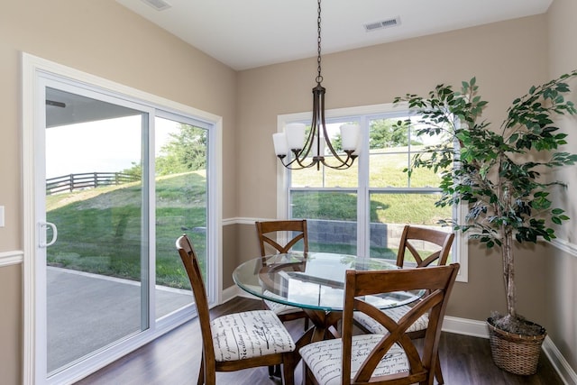 dining room featuring an inviting chandelier, a healthy amount of sunlight, and dark wood-type flooring