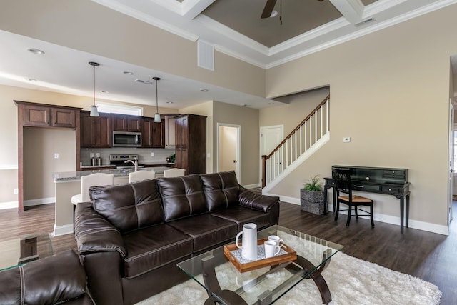 living room with ceiling fan, ornamental molding, coffered ceiling, dark wood-type flooring, and beam ceiling