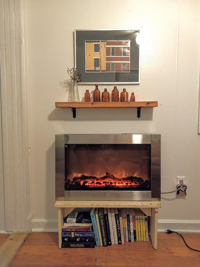 details with a lit fireplace, baseboards, and wood finished floors