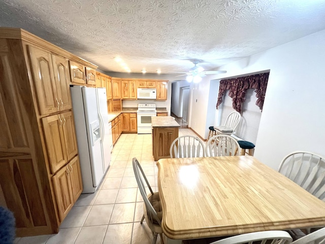 kitchen with a textured ceiling, white appliances, light tile patterned floors, and ceiling fan