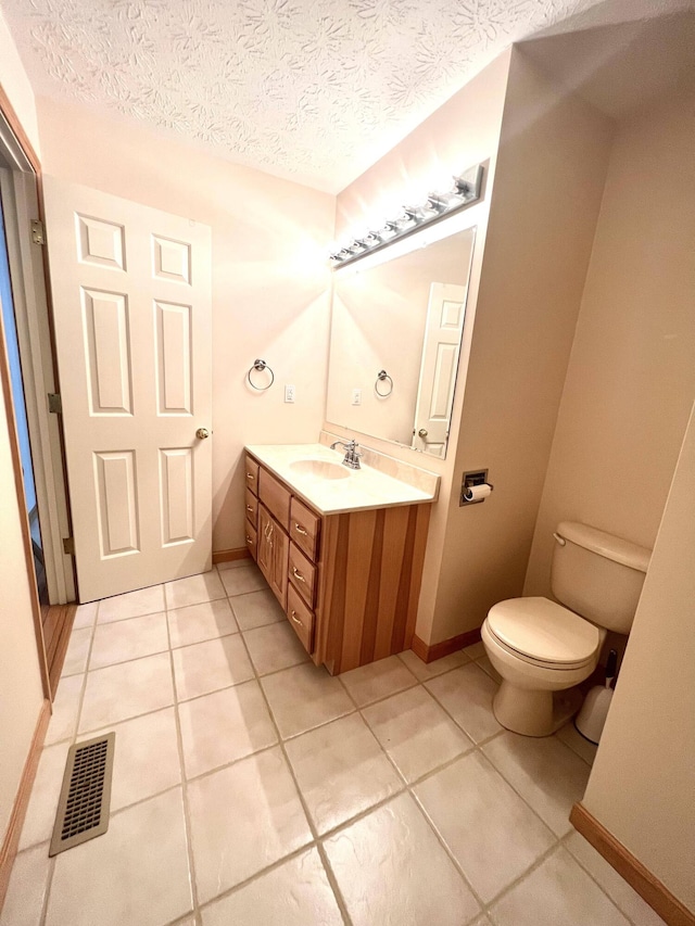 bathroom with tile patterned flooring, vanity, a textured ceiling, and toilet