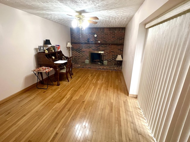 living area with ceiling fan, a textured ceiling, and light hardwood / wood-style flooring