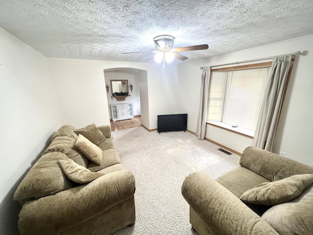 carpeted living room with a textured ceiling and ceiling fan