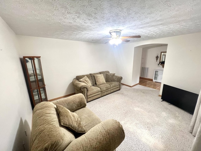 living room featuring a textured ceiling, carpet floors, and ceiling fan