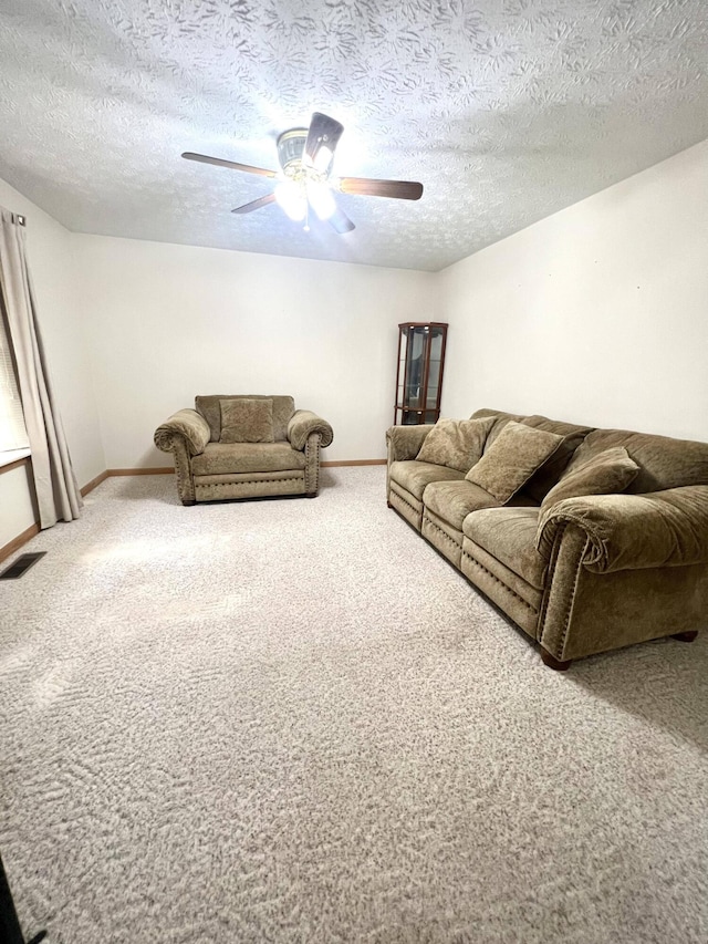 living room featuring a textured ceiling, carpet floors, and ceiling fan