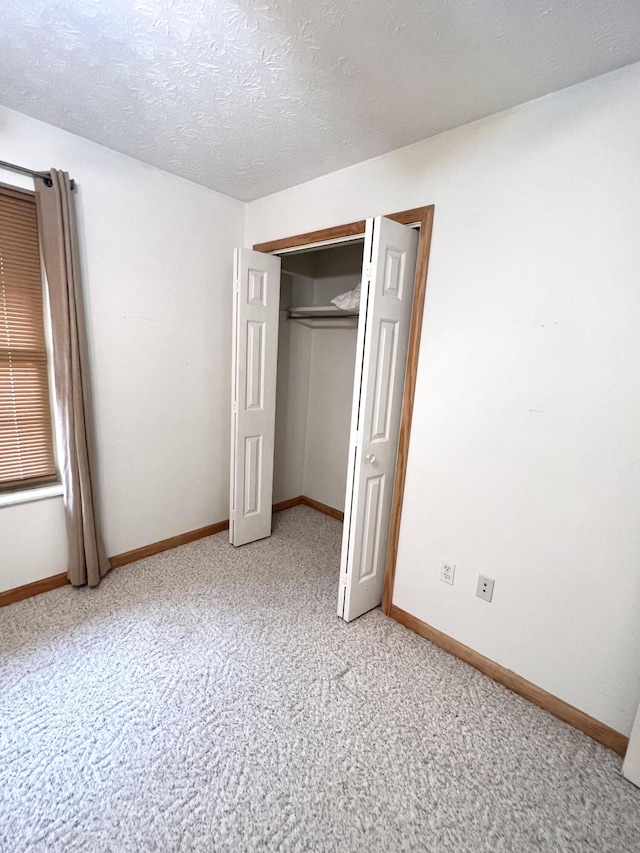 unfurnished bedroom with carpet flooring, a textured ceiling, and a closet