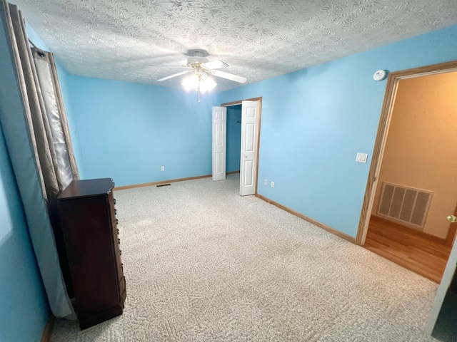 empty room with carpet flooring, ceiling fan, and a textured ceiling