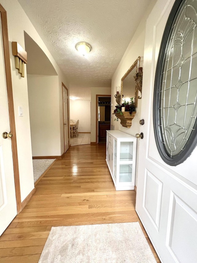 hallway with light hardwood / wood-style flooring and a textured ceiling