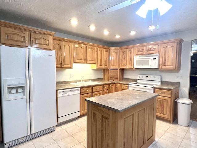 kitchen with sink, a kitchen island, light tile patterned flooring, and white appliances