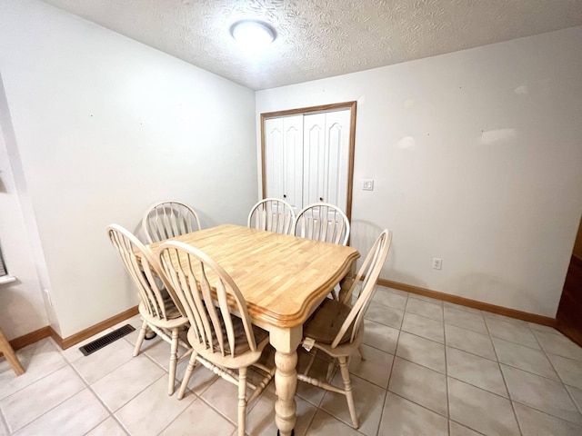 tiled dining space with a textured ceiling