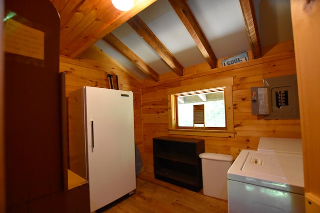 laundry area featuring wooden walls, washing machine and dryer, and light hardwood / wood-style flooring