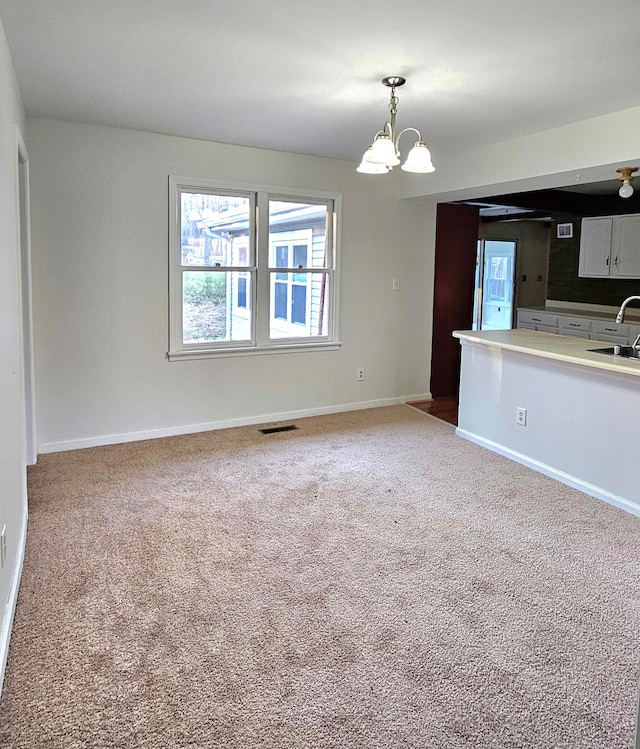 unfurnished living room with an inviting chandelier, sink, and carpet floors