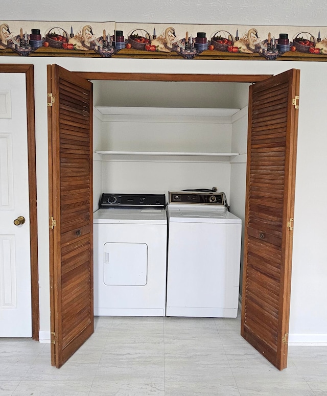 laundry area with washing machine and clothes dryer and light tile flooring