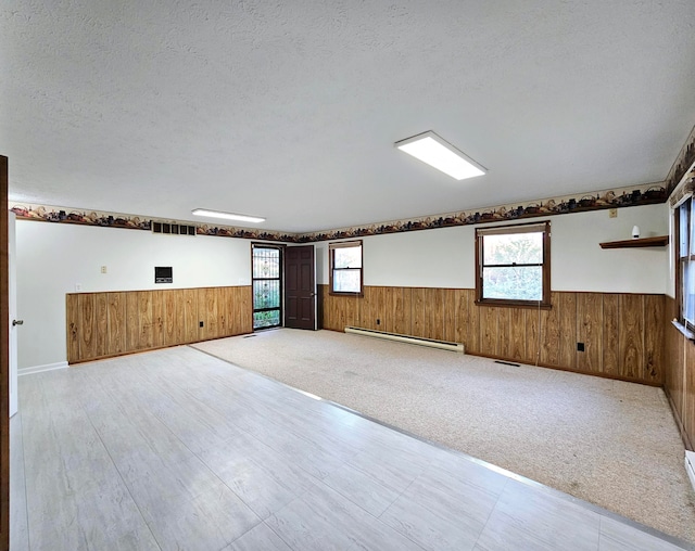 basement with a textured ceiling, light colored carpet, and a baseboard radiator