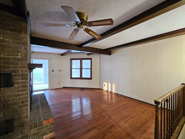 unfurnished room featuring ceiling fan, a textured ceiling, dark wood-type flooring, and beamed ceiling