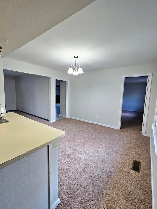 carpeted empty room with an inviting chandelier