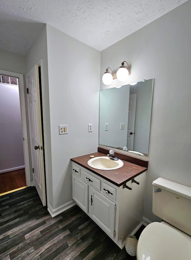 bathroom with a textured ceiling, toilet, oversized vanity, and hardwood / wood-style flooring