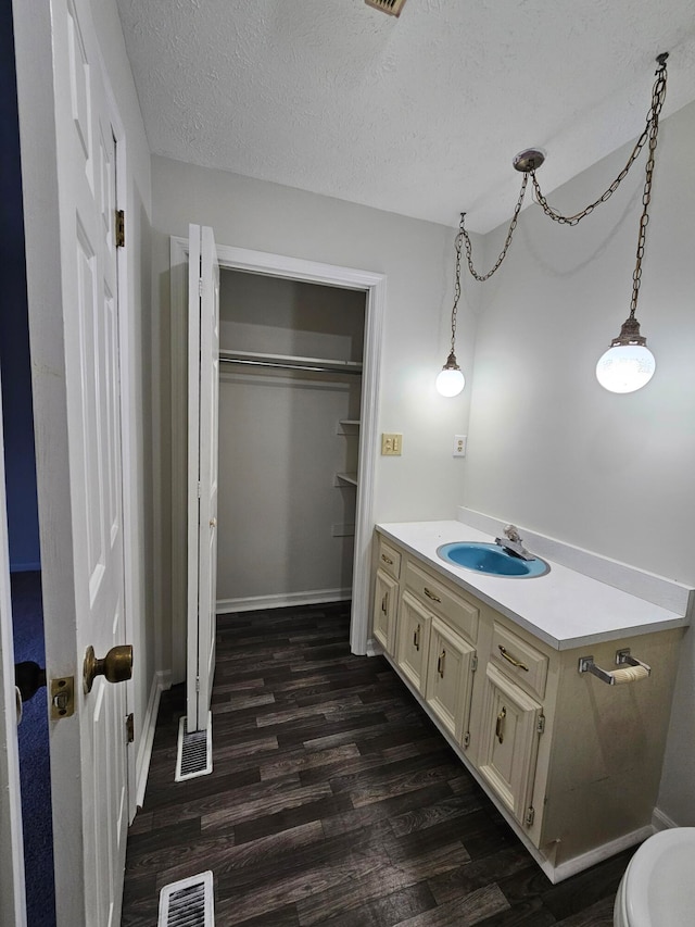 bathroom with a textured ceiling, hardwood / wood-style floors, toilet, and vanity