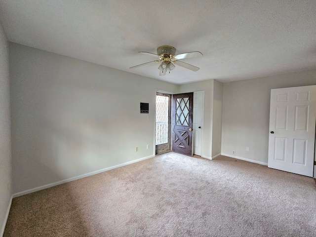 carpeted spare room featuring ceiling fan and a textured ceiling