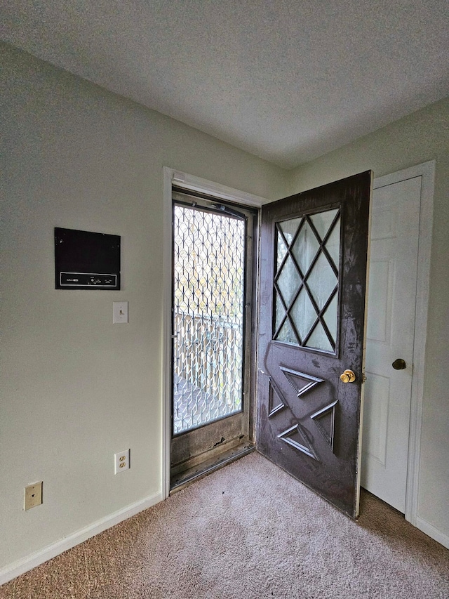 entrance foyer with a textured ceiling and dark carpet