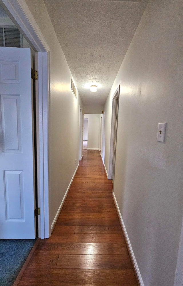 hallway featuring a textured ceiling and dark wood-type flooring